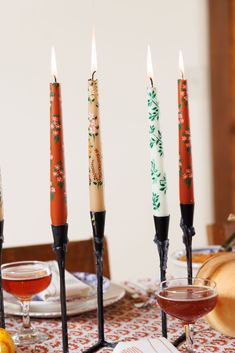 four candles are sitting on a table with plates and glasses