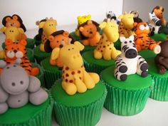 cupcakes decorated with different types of animals on top of green frosted muffins