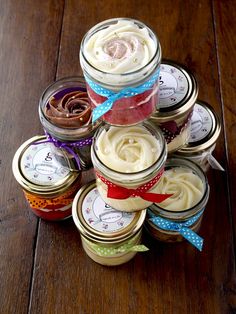 a stack of jars filled with different types of cake in them on top of a wooden table