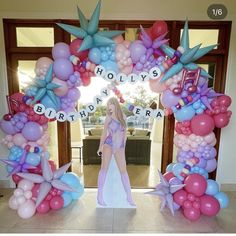 a woman is standing in front of a birthday arch with balloons and letters on it