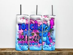 three toothbrush holders with graffiti on them sitting on a wooden shelf in front of a white wall