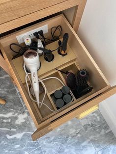 an open drawer with hair dryers, combs and other items in it on the floor