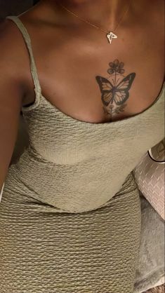 a woman with a butterfly tattoo on her chest and arm, wearing a tan dress