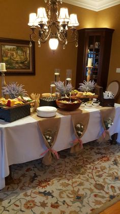 a dining room table covered in food and wine glasses on it's side, with an ornate chandelier hanging from the ceiling