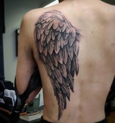 the back of a man's shoulder with an angel wing tattoo on it