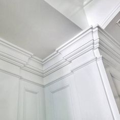 the corner of a room with white walls and molding on the ceiling is shown