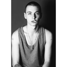 black and white photograph of a young man with tattoos on his arms, wearing a tank top