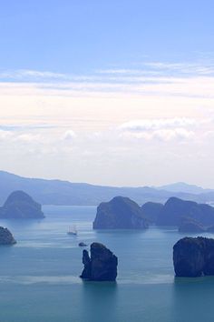 an island in the middle of water surrounded by land and mountains with boats on it