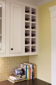 a kitchen with white cabinets and shelves filled with wine bottles on top of a counter