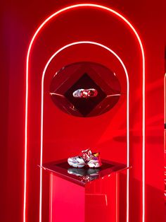 a pair of shoes sitting on top of a glass table next to a red wall