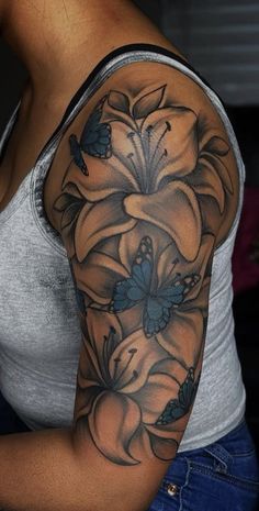 a woman's arm with flowers and butterflies on the back of her shoulder, which is covered in black ink