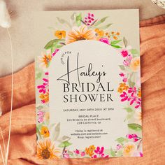 the floral bridal shower is on top of an orange sheet with white and pink flowers