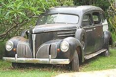 an old car is parked in the grass