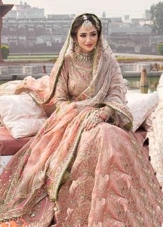 a woman sitting on top of a bed wearing a pink dress and headpieces