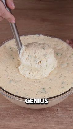 a person dipping something into a bowl with a spoon in it that says genius on the side