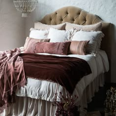 a bed with pillows and blankets on it in a room next to a lamp shade