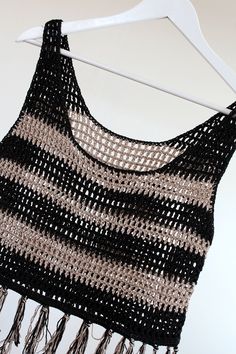 a black and white crochet top hanging on a clothes line with a hanger