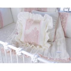 a white crib with pink and white pillows on it