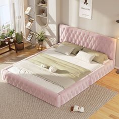 a bedroom with a pink bed and wooden floors in the room, along with two lamps on either side of the bed