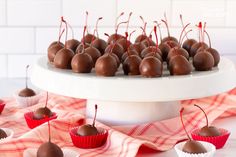 chocolate covered candies are arranged on a white cake platter with red striped napkins