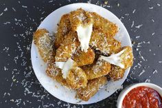 a white plate topped with fried food next to a small bowl of ketchup