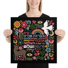 a woman holding up a black poster with flowers and birds on it, while smiling at the camera