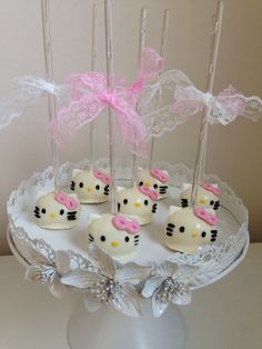 hello kitty cake pops are sitting on a white platter with pink bows and ribbons