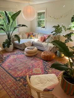 a living room filled with lots of furniture and large potted plants on top of a rug