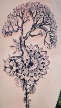 a tree tattoo on the back of a woman's lower back, with flowers and leaves around it