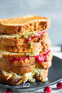 a stack of grilled cheese sandwiches on a black plate with cranberry sauce