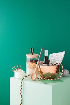 a bowl with spoons, salt and pepper shakers in it on a green surface