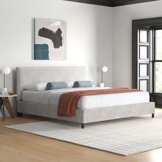 a white bed sitting in a bedroom on top of a hard wood floor next to a window