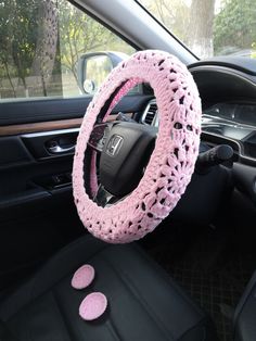 a car steering wheel cover with pink crochet on it's center console