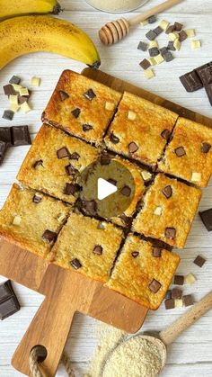 chocolate chip cookie bars cut into squares on a cutting board next to bananas and spoons