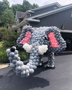 an elephant made out of balloons in front of a house