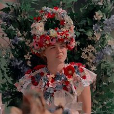 a woman with flowers in her hair wearing a floral headdress and looking at the camera