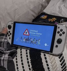 a person holding a nintendo wii game controller in front of a screen with an animated video game on it