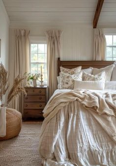 a bedroom with white walls and beige bedding, pillows and blankets on the bedspread