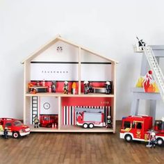 a toy fire truck and ladder next to a doll house with toys on the floor