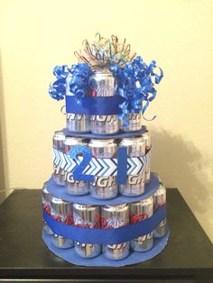 a tiered cake made out of cans with blue ribbons