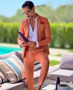 a man in an orange suit and sunglasses sitting on a couch next to a pool