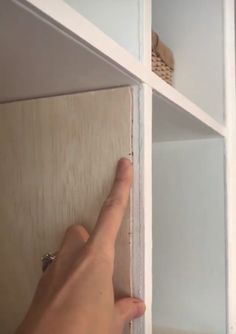 a person's hand is pointing at the door handle on a cabinet with glass doors