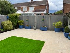 a backyard with grass and potted plants in front of a fenced in area