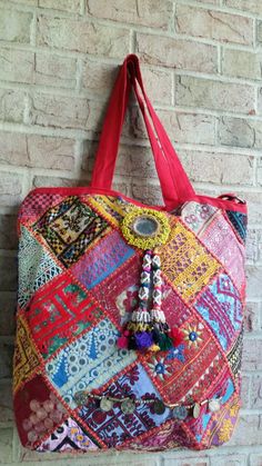 Multi Colored Thread boho Banjara extra large shoulder bag with white beaded tassels. This bag has the multi coloured beaded motif to accentuate the beauty and vintage Indian embroidered textiles were carefully brought together and made into large totes.  There is a zip chain for closure to keep your belongings safe.  They look equally good on the beach with a bikini, or in the city with an edgy leather jacket.  Both sides have a different design to give you an option to carry the bag either ways.The currency coin chain is an exceptional accessory on the front completing the whole look. Bohemian Tribal  and Unbeatable Indian Ethnic patchwork Bags & handbags are a hit with stylists all over the world. . This perfectly sized extra large shoulder bag is an ensemble from a selection of assorte Red Bohemian Shoulder Bag With Tassels, Bohemian Rectangular Bag With Tassels, Bohemian Rectangular Bags With Tassels, Bohemian Patchwork Bags For Summer, Bohemian Hobo Bag With Tassels, Traditional Beach Shoulder Bag With Tassels, Traditional Shoulder Bag With Tassels For Beach, Traditional Tassel Shoulder Bag For Beach, Bohemian Tote Shoulder Bag With Tassels