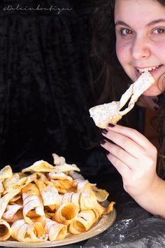 a woman eating food from a plate with tortilla shells on the table next to her