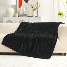 a white couch with a black blanket on it