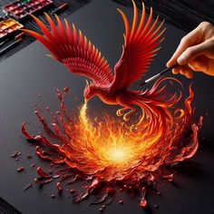 a person is drawing on a piece of paper with fire and flames in the shape of a bird