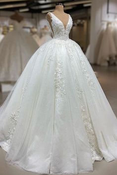 a white wedding dress on display in a storeroom with other dresses and gowns behind it