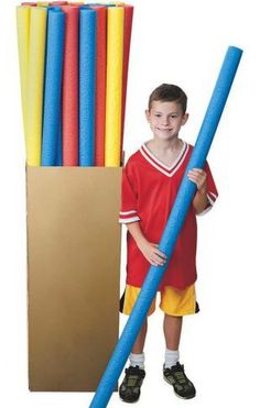 a young boy holding a giant blue tube next to a cardboard box filled with colored plastic tubes