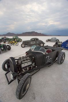 a group of cars sitting on top of a sandy field